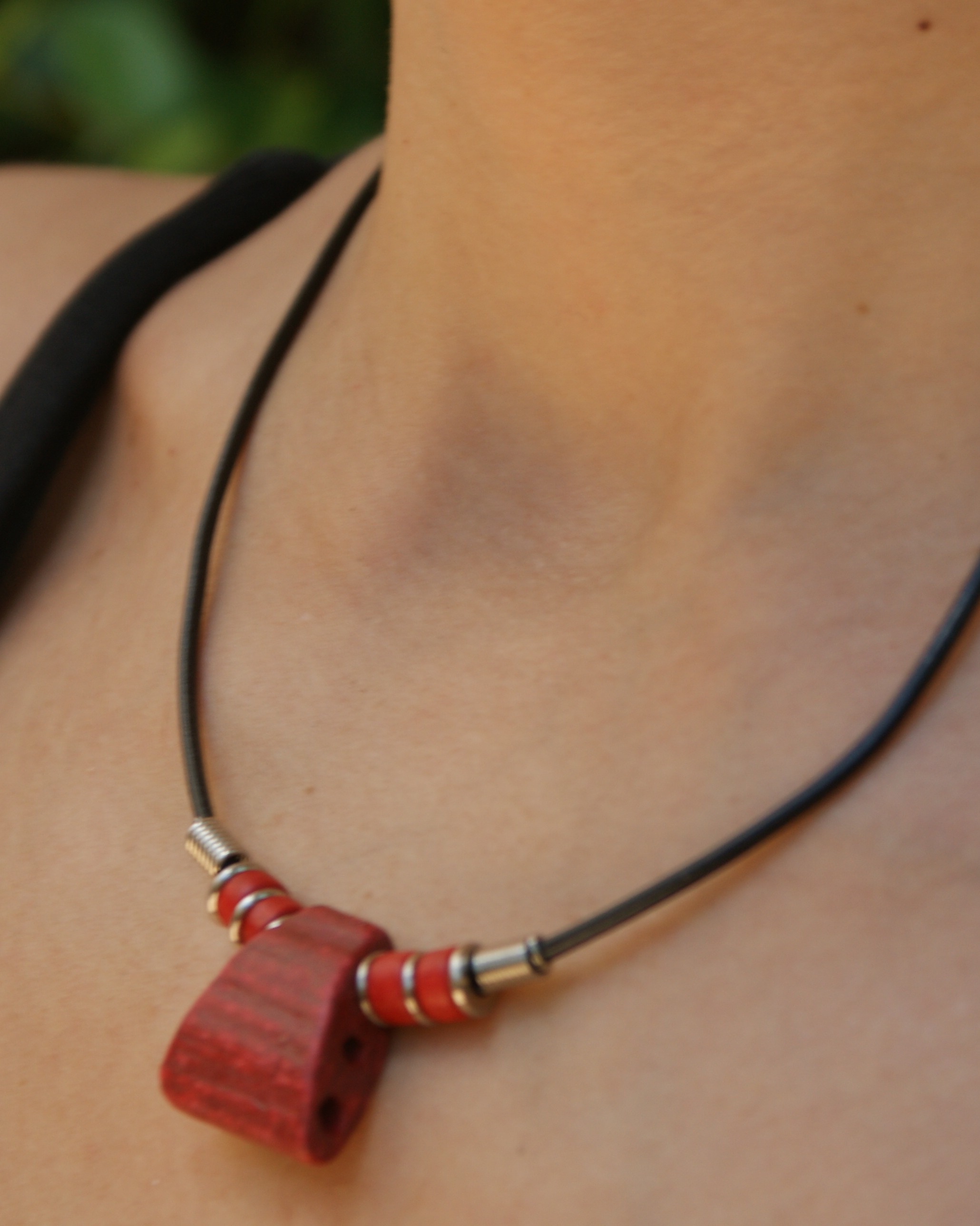 Black cord necklace with a red geometric pendant. (alternate view)